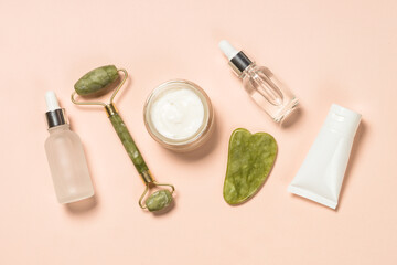 Wall Mural - cosmetic products - jade roller and gua sha massager with cream and serum bottles. spa background.