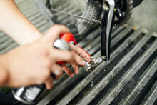 Crop Man Cleaning Bicycle Pedal In Workshop