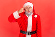 © khosrork - Elderly man with gray beard in santa claus costume crossed eyes, showing stupid gesture, looking at camera with condemnation and blaming for insane plan. Indoor studio shot isolated on red background.