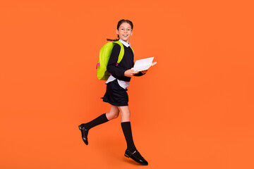 Canvas Print - Full body photo of cheerful brunette braids haired girl jump up hold book wear bag isolated on orange color background