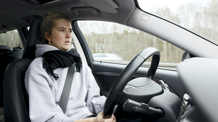 Wall Mural - Young woman with natural look driving a passenger car on a German highway. The young woman shows various emotional reactions to the traffic event.