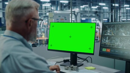 Leinwandbilder - Car Factory Monitoring Office: Male Chief Automotive Engineer Sitting at the Desk Working on Green Screen Chroma Key Computer. Automated Robot Arm Assembly Line Manufacturing Vehicles