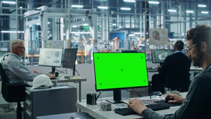 Leinwandbilder - Car Factory Office: Caucasian Male Automotive Engineer Sitting at His Desk Working on Green Screen Chroma Key Computer. Automated Robot Arm Assembly Line Manufacturing. Over Shoulder Medium Shot