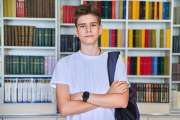 Wall Mural - Single portrait of serious confident male student teenager looking at camera in library