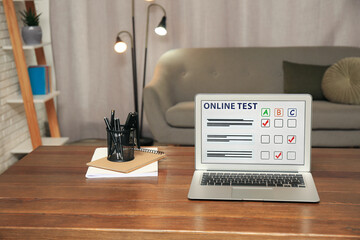 Wall Mural - Laptop with online test and stationery on table at home