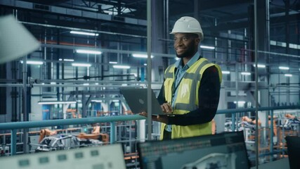 Leinwandbilder - Car Factory: Professional Male Automotive Engineer Wearing Hard Hat, Walking, Using Laptop. Monitoring, Control, Equipment Production. Automated Robot Arm Assembly Line Manufacturing Electric Vehicles