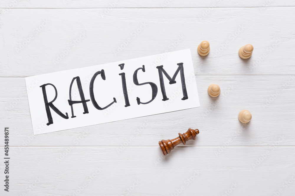 Different chess pieces on white wooden background. Racism concept