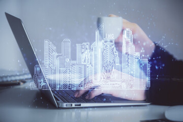 Double exposure of woman hands typing on computer and buildings drawing. Smart-city concept.