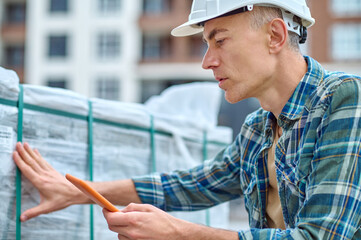 Poster - Serious worker in a hardhat touching construction materials