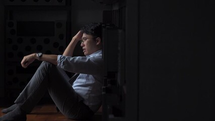 Stressed Asian businessman sitting on the floor holding financial bill think of debt and business problem. Unemployed man worry about money management. Mental health and financial problem concept