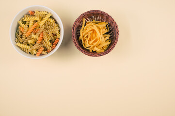 Canvas Print - Top view of tri-color rotini and fettuccine pasta on a bowl isolated on brown background