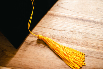Wall Mural - black graduation cap and yellow tassel place on wooden table