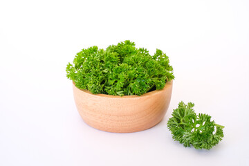 side view composition with fresh green curley parsley leaves in the wooden bowl isolated on white ba