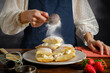 powdered icing sugar sprinkling from a sieve in woman's hand, cooking sweet puff pastry with cream