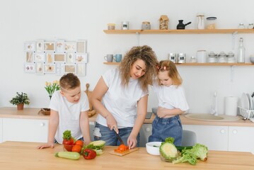 mother with children preparing vegetable salad at home