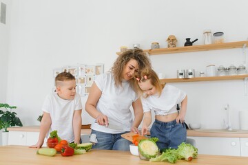 Young mother and her two kids making vegetable salad