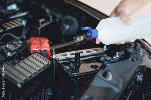 A man holding and add water to distilled the car battery maintenance and inspections for extended service life of car