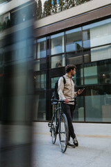 Wall Mural - Man using a cellphone while walking with his bicycle in the city