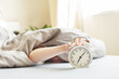 © stopabox - boy lying on the bed and stopping alarm clock in morning. childs hand reaching for the alarm clock to turn it off.