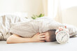 © stopabox - boy lying on the bed and stopping alarm clock in morning. childs hand reaching for the alarm clock to turn it off.