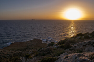 Sticker - Peaceful beautiful sunset along the coast of Qrendi, Malta, with the island of Filfla in distance.