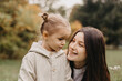 © Ananass - Young happy and smiling mom with her little daughter in arms hugging and kissing spending a weekend on a walk in autumn park. selective focus, noise effect, Autumnal mood