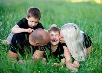 Two parents and two children lying on green grass in Summer