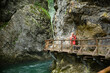 Young female photographer in colourful jacket hiking a trail along a clear river through the Vintgar Gorge in Slovenia