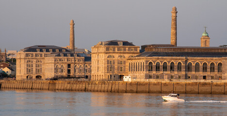 Wall Mural - Plymouth, Devon, England, UK. 2021. The Royal William Yard a Grade 1 listed site formerly Royal Navy victualling bulidings seen across River Tamar from Cremyll landing stage, Cornwall. Evening light.