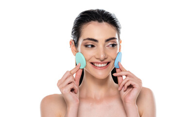 cheerful woman holding blue beauty sponges isolated on white