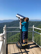 © Anna - Vertical image of boy looking into big iron binocular on mountain viewpoint.