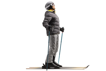 Canvas Print - Full length profile shot of a man in a skiing jacket, boots and helmer with a pair of skis