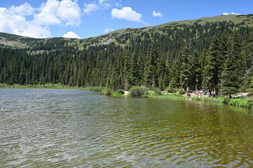 Wall Mural - Distant hikers enjoy view of Hassell Lake in Arapaho National Forest, Colorado on sunny summer afternoon.