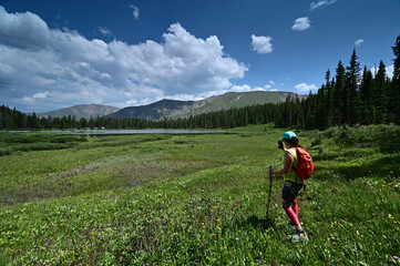 Wall Mural - Young female hiker photographs Hassell Lake in Arapaho National Forest, Colorado on sunny summer afternoon.