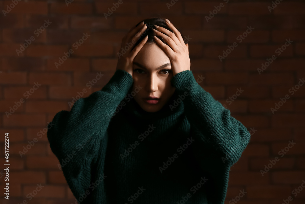 Depressed young woman on dark background