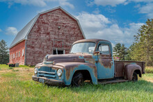 Vintage Red Barn With Abandoned Truck In A Farmyard On The Prairies In Saskatchewan