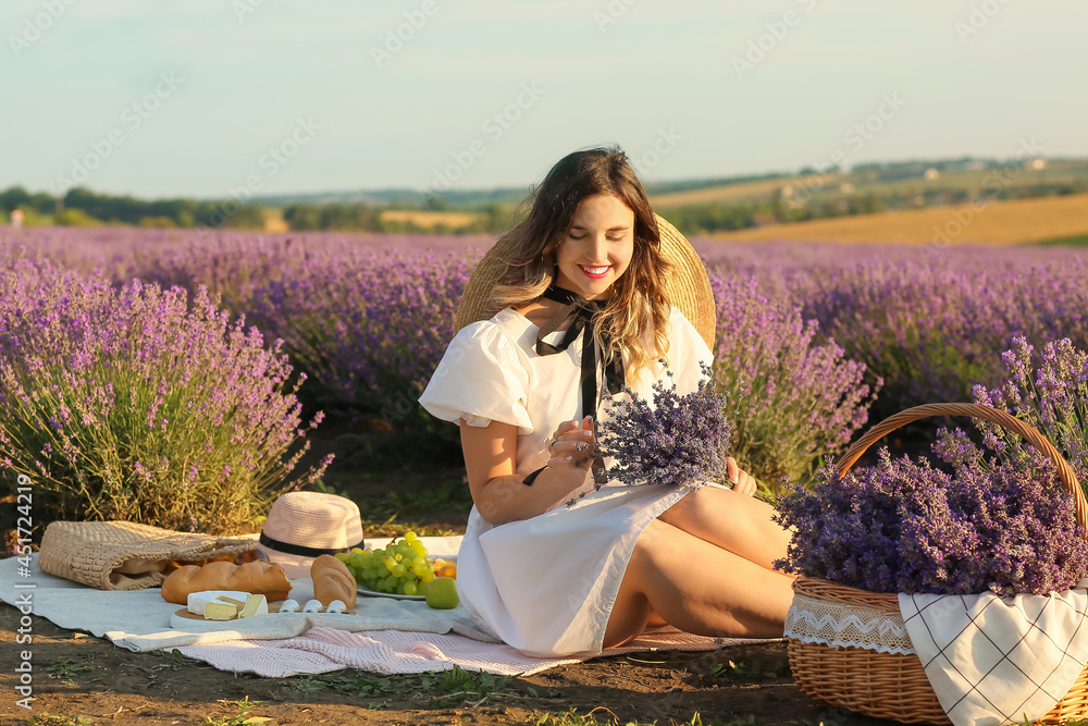 Beautiful young woman having picnic in lavender field