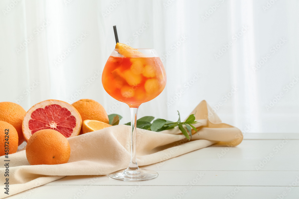 Glass of Aperol spritz cocktail on light wooden background