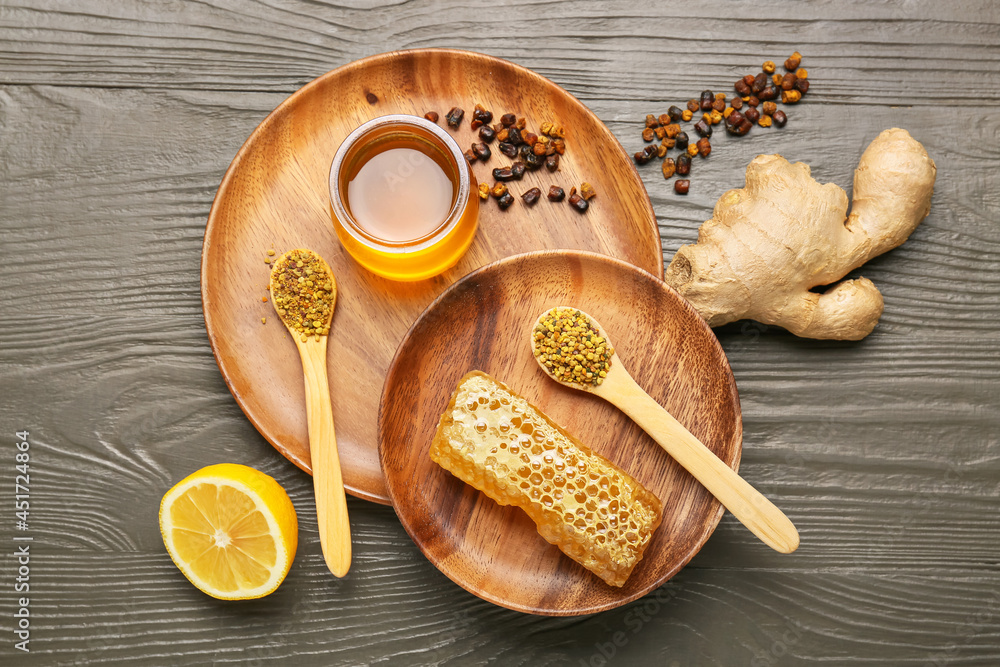 Different bee products with lemon and ginger on wooden background
