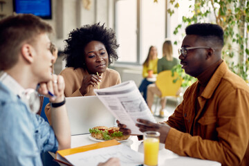 Wall Mural - Group of college students learn together during lunch break in cafeteria.