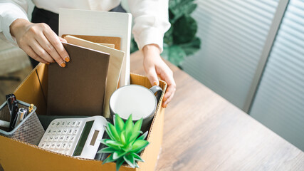 Business woman sending resignation letter and packing Stuff Resign Depress or carrying business cardboard box by desk in office. Change of job or fired from company