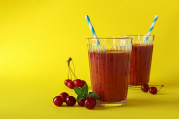 Wall Mural - Glasses of cherry smoothie and ingredients on yellow background