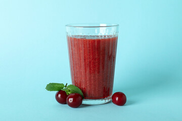 Wall Mural - Glass of cherry smoothie and ingredients on blue background