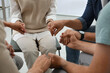 © New Africa - Psychotherapist and group of drug addicted people holding hands together at therapy session, closeup