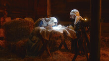 Mary And Joseph Caressing Baby Jesus In Illuminated Manger