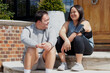 © Anna Neubauer - Young biracial couple with Down Syndrome in active wear and wearable tech sitting on steps and laughing