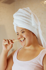 Wall Mural - Young biracial woman with Down Syndrome brushing her teeth with bamboo toothbrush