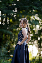 Canvas Print - Long-haired young lady in an elegant dark blue dress is posing in the park