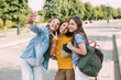 © Sviatlana - Three charming friends take selfies with their phone on the way to school. The concept of friendship. Education, training, back to school
