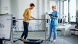 © Gorodenkoff - Hospital Physical Therapy Room: Patient with Injury Walking on Treadmill Holding for Parallel Bars, Professional Physiotherapist Assists, Helps, Trains Disabled Person Do Rehabilitative Physiotherapy